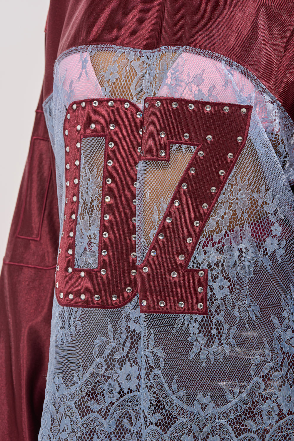 Close-up of the WINNER JERSEY: a maroon two-tone lace top with a bold red "07" and silver studs over light blue floral lace—showcasing mixed textures and sporty-chic style for game-day glam. 7