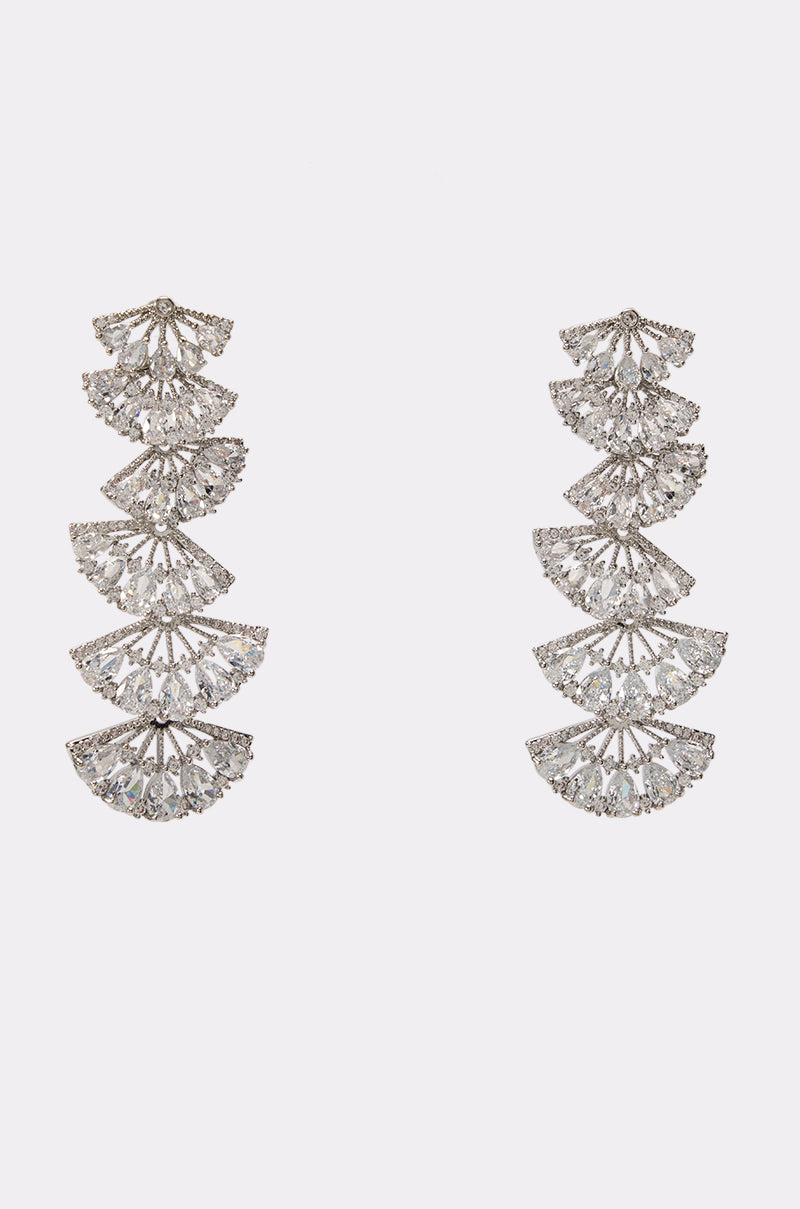 The BIGGEST FAN STATEMENT EARRING features a pair of silver dangle earrings with four stacked fan-shaped segments encrusted in clear gemstones, elegantly presented on a plain white background—an ideal accessory choice for wedding guests.