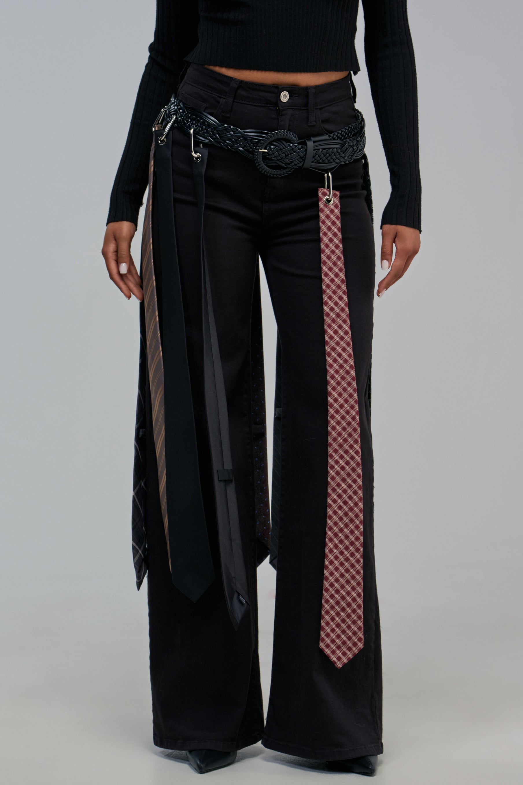 OFFICE HOTTIE BELT made of black woven faux leather worn over black jeans with several satin neckties hanging from the belt loops.