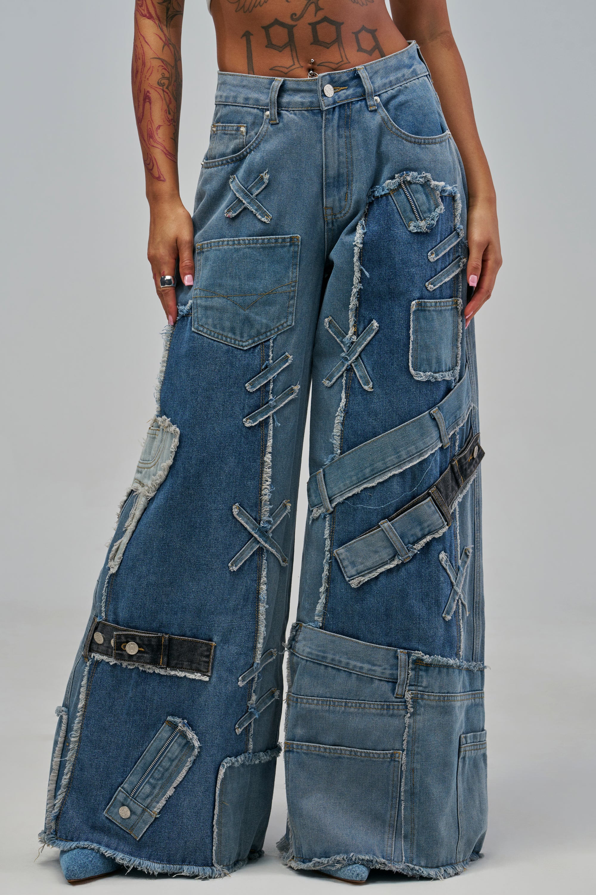 DISTRESSED GIRL DENIM wide-leg patchwork jeans featuring distressed, frayed overlapping denim strips and cross-stitch details.
