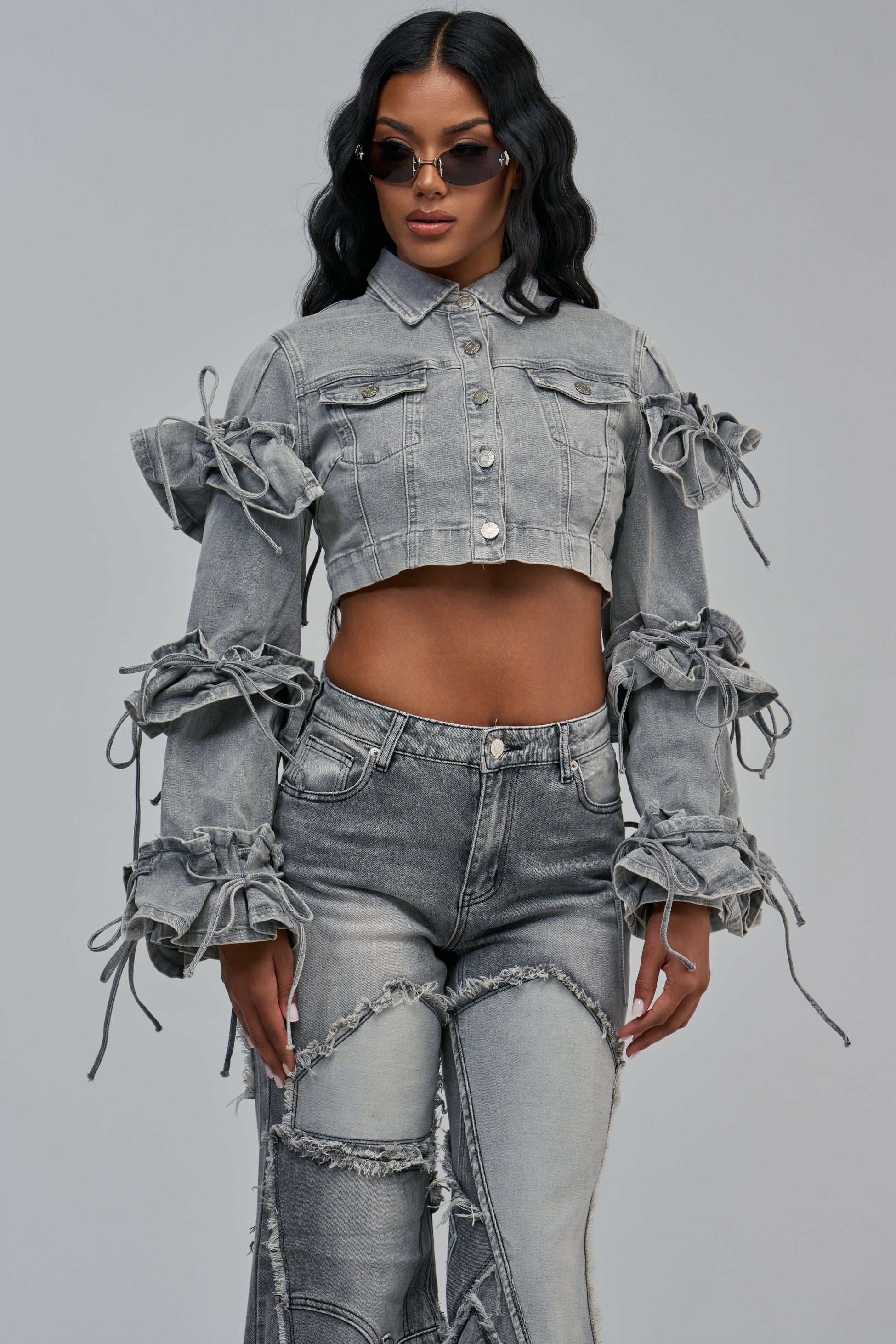 LENNON CROPPED DENIM JACKET IN GREY featuring metal buttons and multiple tied bow details along the ruffle sleeves.