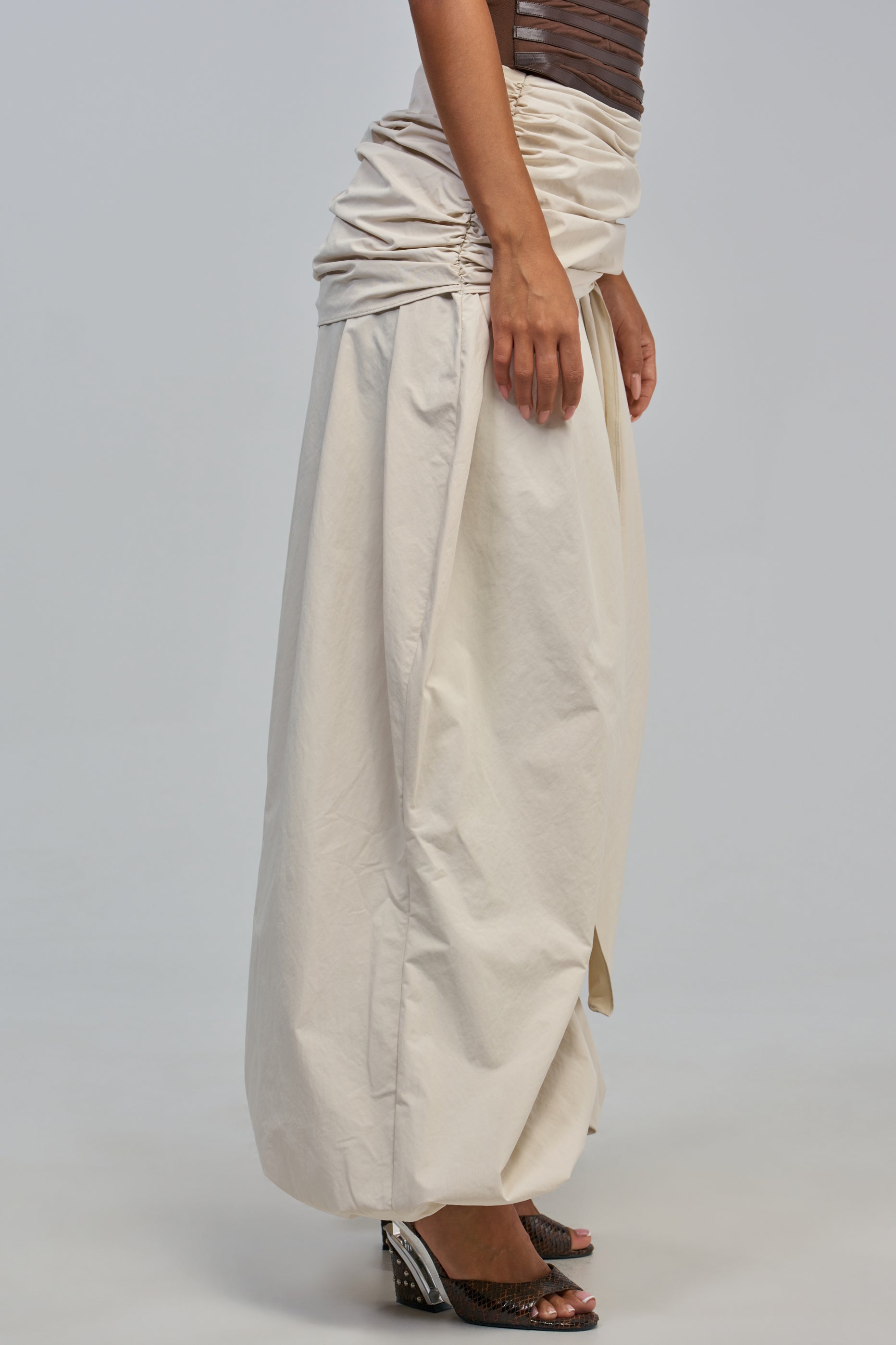 Wearing the NOT MY TYPE TROUSER, a person stands on a plain light background, styled with a shiny brown strapless top and open-toe black heeled shoes.