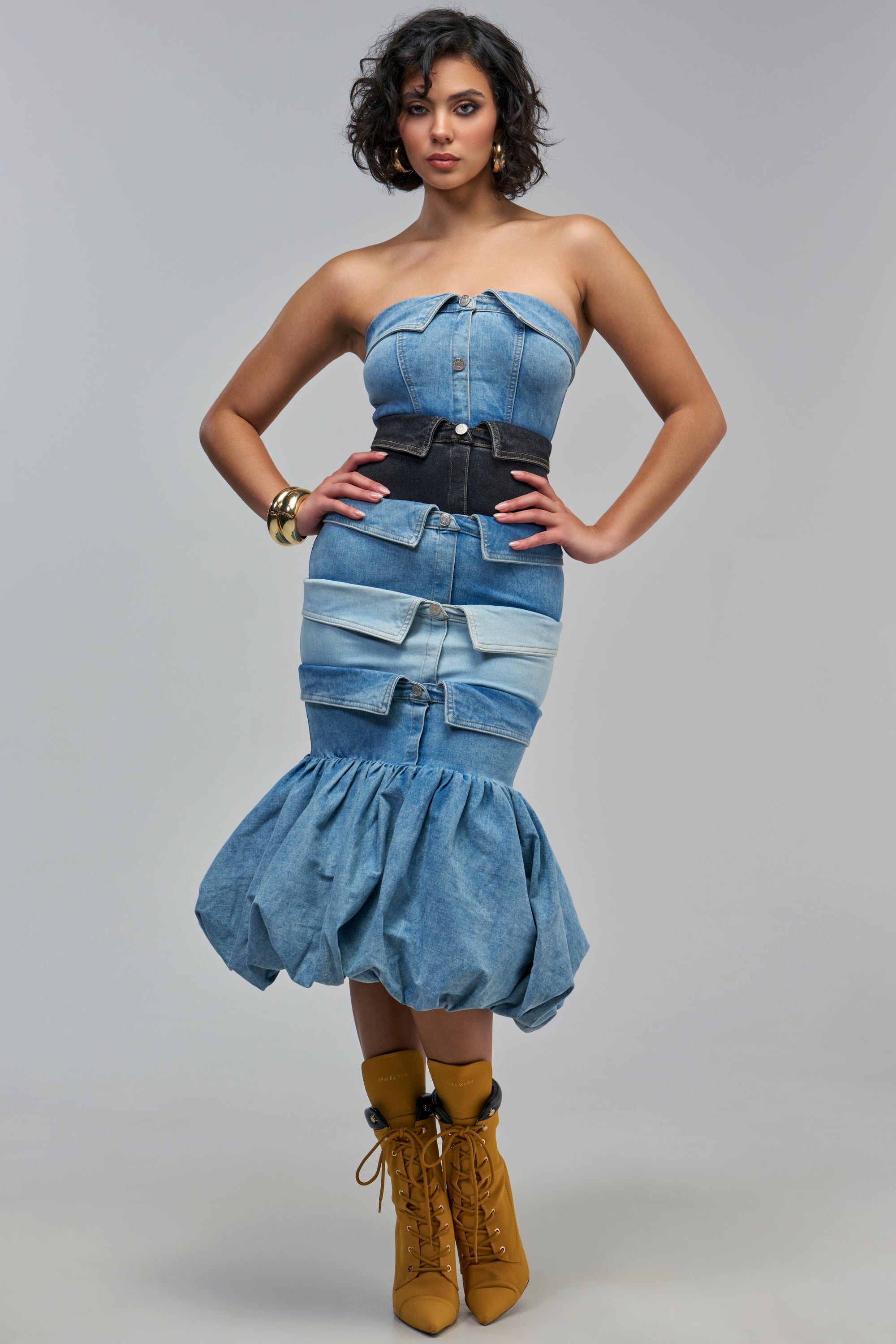 A BUTTON UP DENIM MAXI DRESS in a strapless paneled patchwork design with a wide black waist belt and a voluminous bubble hem, worn with lace-up tan ankle boots.
