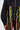 A person models the MARLEY LACE UP BOMBER, a black nylon bomber jacket with vibrant red, yellow, green, white, and orange braided shoelaces threaded through front eyelets. The individual's face is not shown.