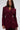 A woman with long brown hair confidently models THE BLUEPRINT ASYMMETRICAL BLAZER, featuring a structured design and wide lapels, against a plain light gray background.