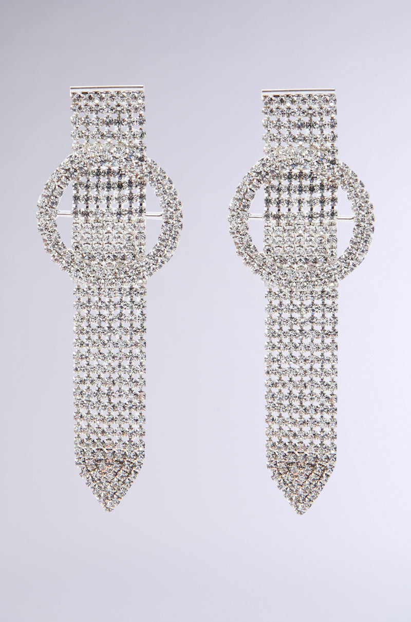 The LOOP ME IN SILVER EARRING showcases silver, gemstone-encrusted circular and rectangular designs. It features dangling strands that create a chainlink accessory vibe, all set against a neutral gray backdrop.