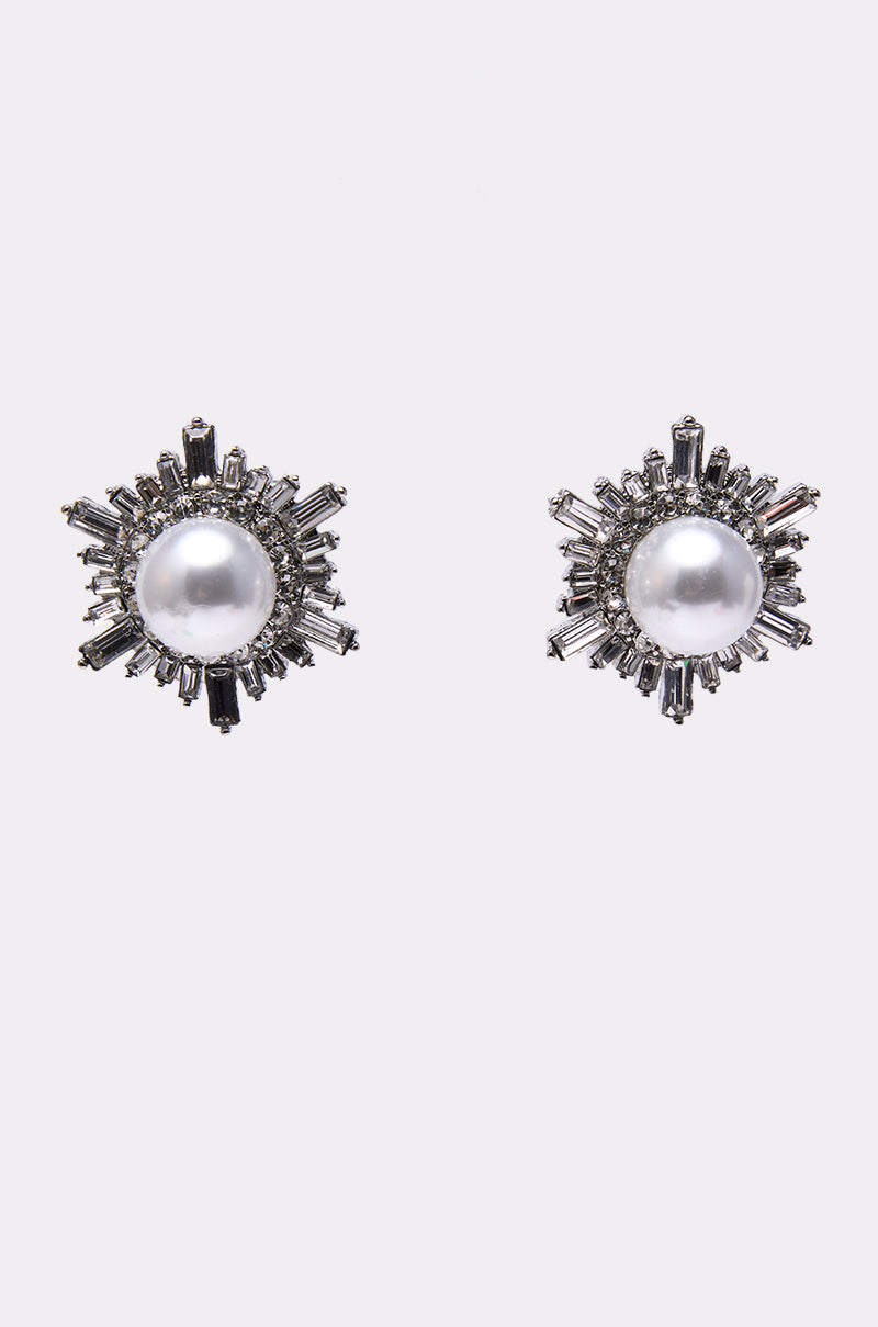 The TAY EARRING showcases oversized round pearls at the center, accented by a sunburst motif with clear rhinestones on a silver-toned setting, shown against a plain white background.