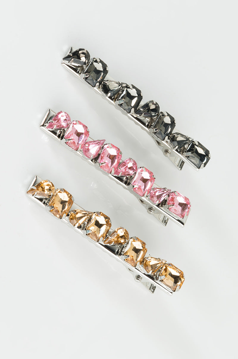 Three hair clips from the 3 PIECE SET RHINESTONE HAIR PINS are aligned vertically on a white background. Each clip features large, faceted gemstones: the top clip with dark gray stones, the middle with pink stones, and the bottom with light brown stones. The clips have a metallic silver base.