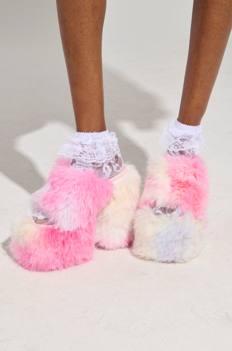 A person dons the GIRLY POP LACE RUFFLE SOCKS IN WHITE, paired with fluffy platform slippers showcasing a vibrant mix of pink, white, and light blue hues against a simple light backdrop—a perfect fusion of whimsy and style.