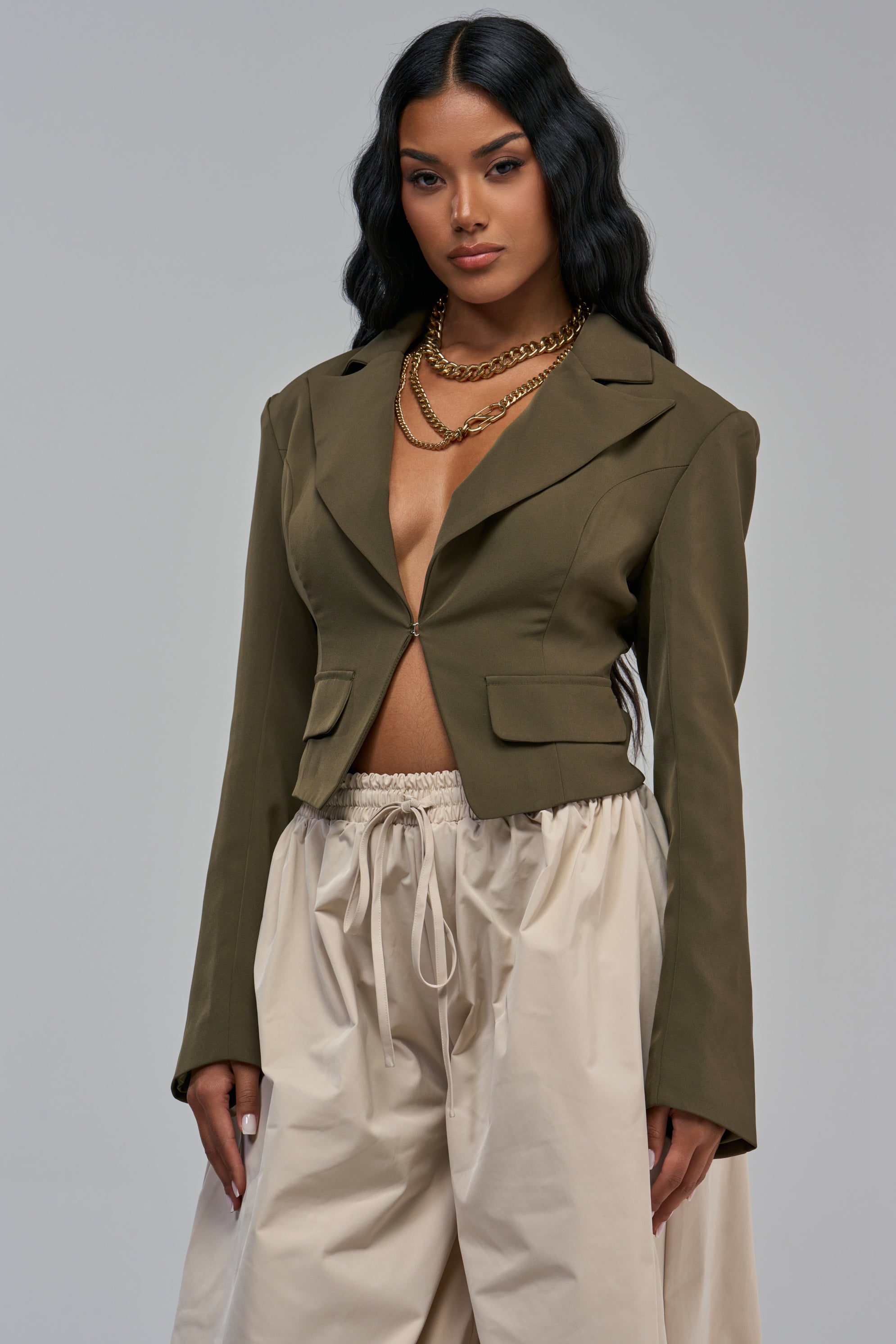 An EASY BREEZY FITTED BLAZER IN OLIVE worn with beige drawstring trousers and layered gold chain necklaces.