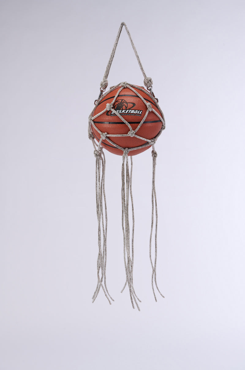 The COURTSIDE BLING BASKETBALL PURSE features a basketball encased in a macrame-style net made of thin, braided ropes, hanging from a loop at the top. Several long, knotted strands of rope dangle freely from the net, giving it the unique flair of a decorative hanging piece.
