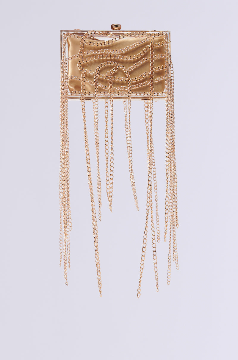 THE REAL RELATE CHAIN CLUTCH, a gold rectangular clutch with a textured surface, hangs against a white background. It features multiple long, delicate gold chains draping down its edges, creating an elegant fringe effect like that of an exquisite crossbody handbag.