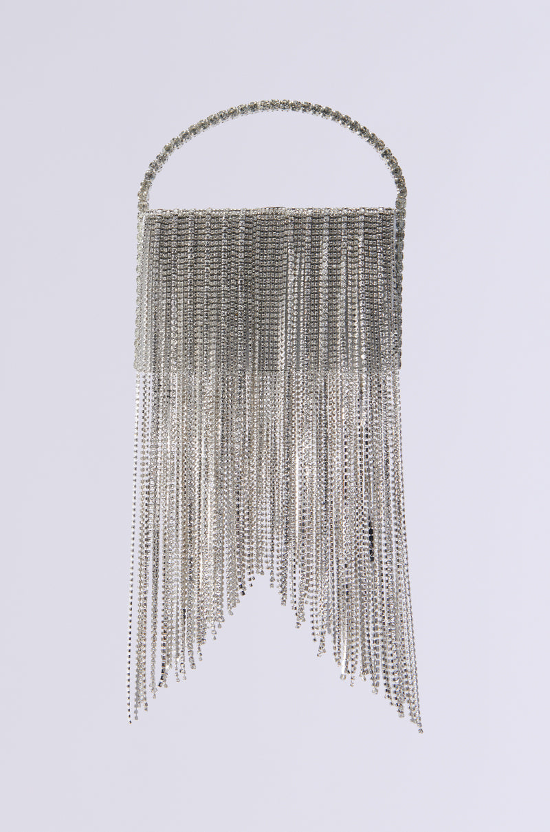 The EXPENSIVE TASTE BLING PURSE features a sophisticated silver design, with a chainlink fringe that creates a dynamic shimmer. Its rhinestone-studded top handle adds elegance to the intricate look, all set against a plain white background.