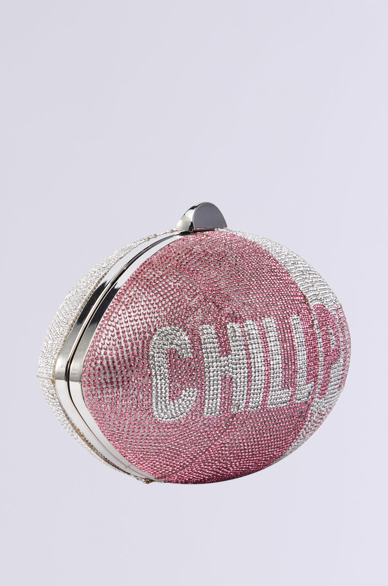 The TAKE A CHILL PILL CLUTCH is a round, pink and silver glittery purse with rhinestones and a visible "CHILL" on the front. It includes a detachable metallic chain link strap for versatile styling.