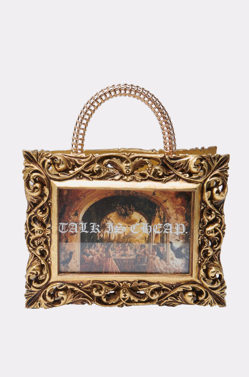 The TALK IS CHEAP FRAME BAG pairs ornate metallic gold edges and chain handles with a classical painting print and bold "TALK IS CHEAP" text, fusing baroque-inspired elegance and modern style.