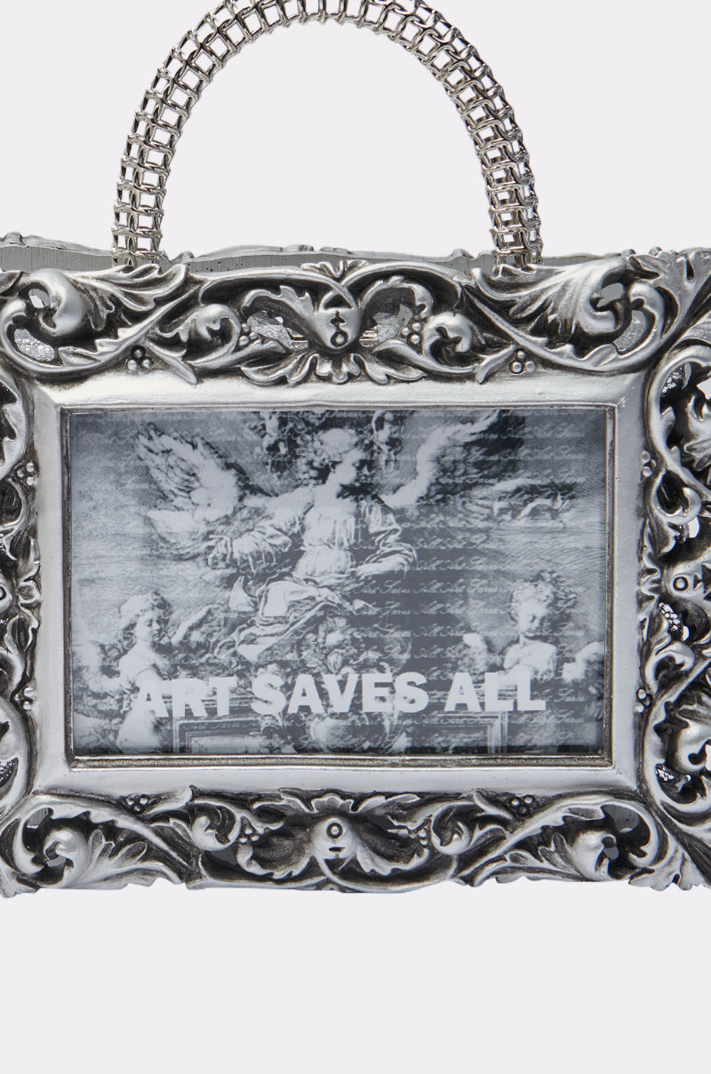 The ART SAVES FRAME BAG is an ornate silver baroque frame purse with a chain handle, featuring a black-and-white image of classical sculptures and “ART SAVES ALL” printed below for a bold statement accessory.