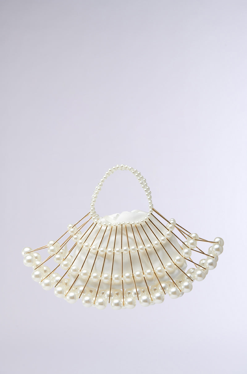 The DIVINE DREAMS PEARL PURSE is a distinctive handbag with a fan-shaped design crafted from metallic gold rods embellished with pearls. A beaded handle of shimmering pearls tops the purse, while pearl accents decorate the rod ends against a simple, light gradient background. 5