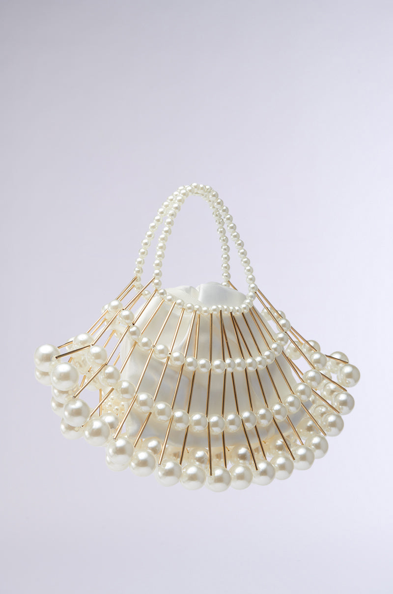 Discover the DIVINE DREAMS PEARL PURSE, a sculptural handbag made from gold rods and pearlescent beads in concentric circles. The handles shimmer with pearls on a light grey background, embodying elegance. Now with a detachable shoulder strap for versatility. 7