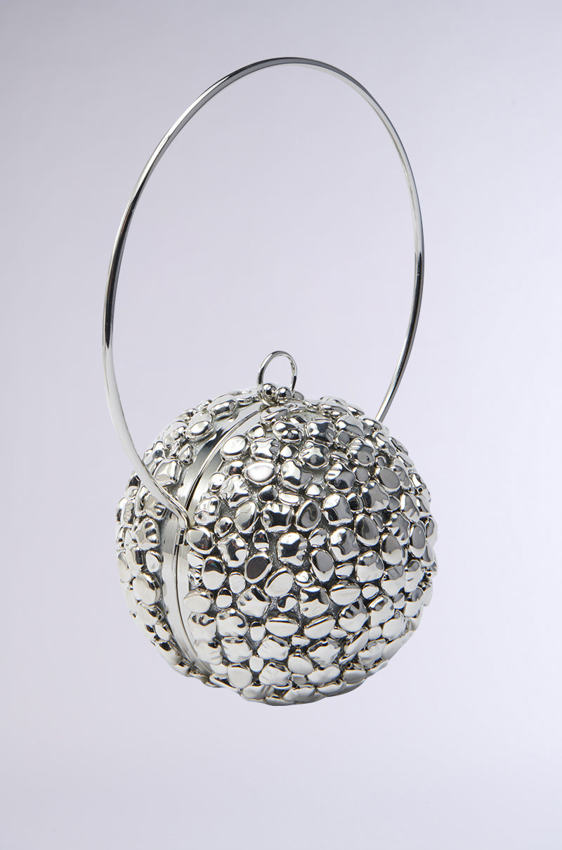The TO THE FUTURE METAL PURSE is a spherical handbag adorned with metallic silver beads and has a circular, top-hinged handle. This statement accessory resembles a cluster of bubbles, giving any plain background a modern touch.