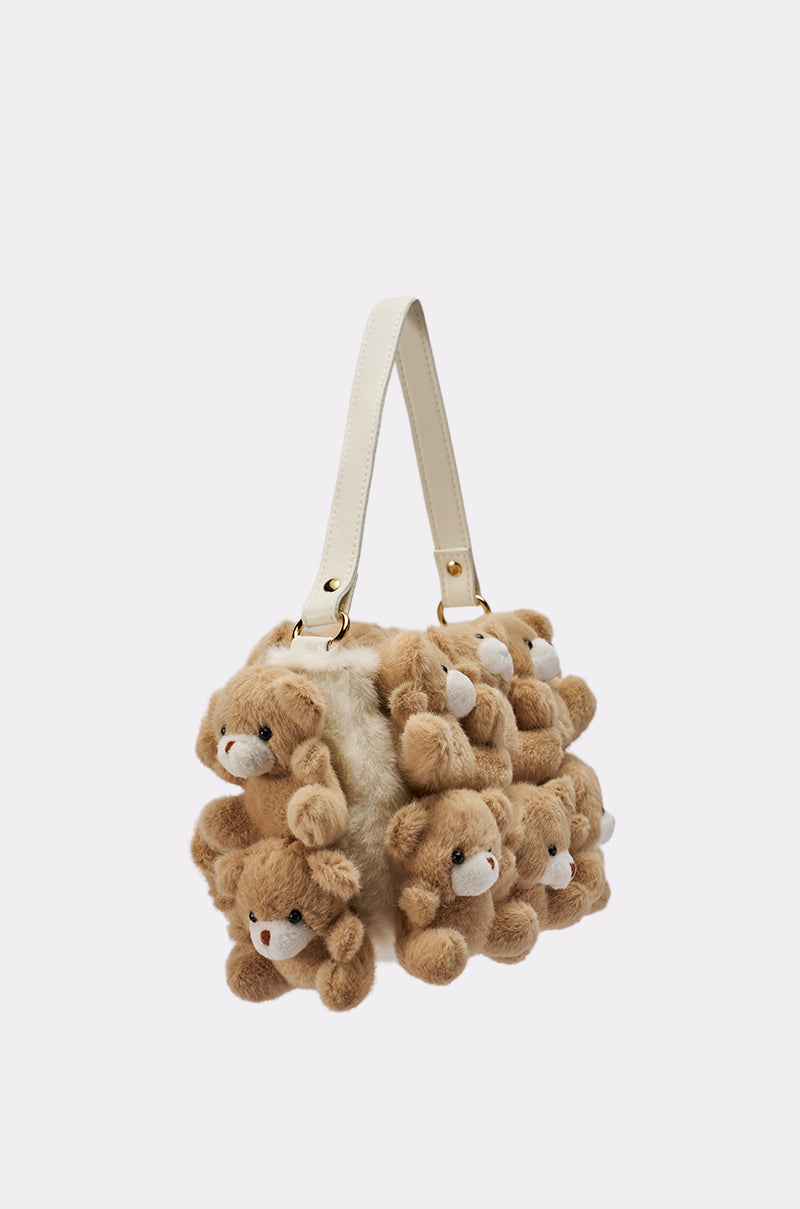 The BEAR WITH ME PURSE features a cream strap and is covered in soft brown faux fur bears with white snouts and small ears, creating a playful, whimsical look.
