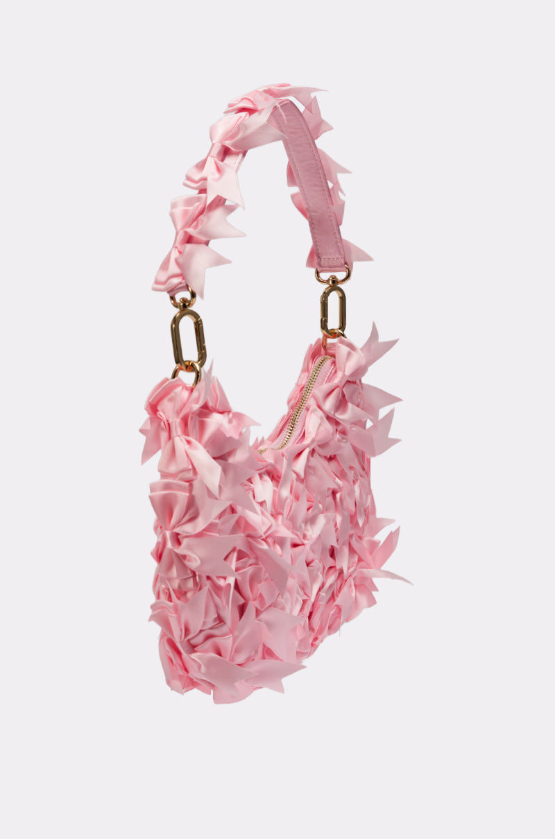 The BOWTIFUL PURSE is a small pink satin handbag with 3D petal accents, a matching handle, and gold hardware—standing out elegantly against a plain light background. 4