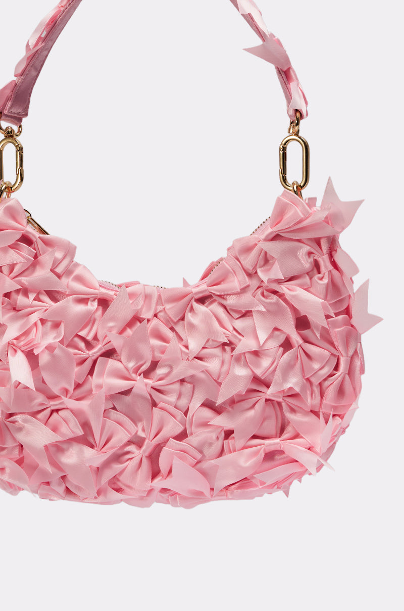 The BOWTIFUL PURSE is a pink satin handbag adorned with multiple fabric bows and elegant gold hardware, shown on a simple white background. 5