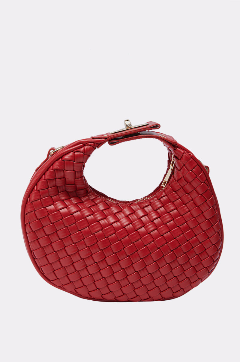 The CARSON WOVEN PURSE is a round, red faux leather bag featuring a zipper closure and small top handle, shown against a plain light background.