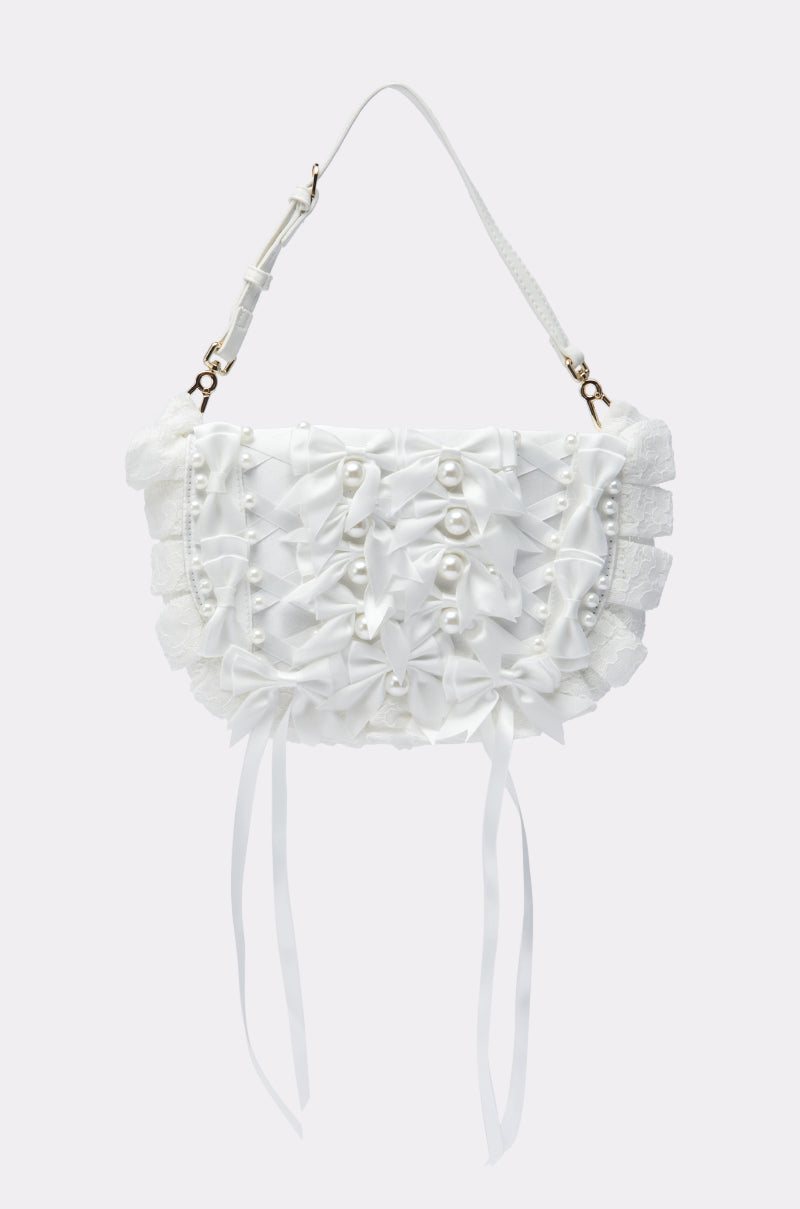 The MARIE BOW PURSE is a white shoulder bag adorned with layered bows, pearl details, ruffled edges, and two long ribbon tails.