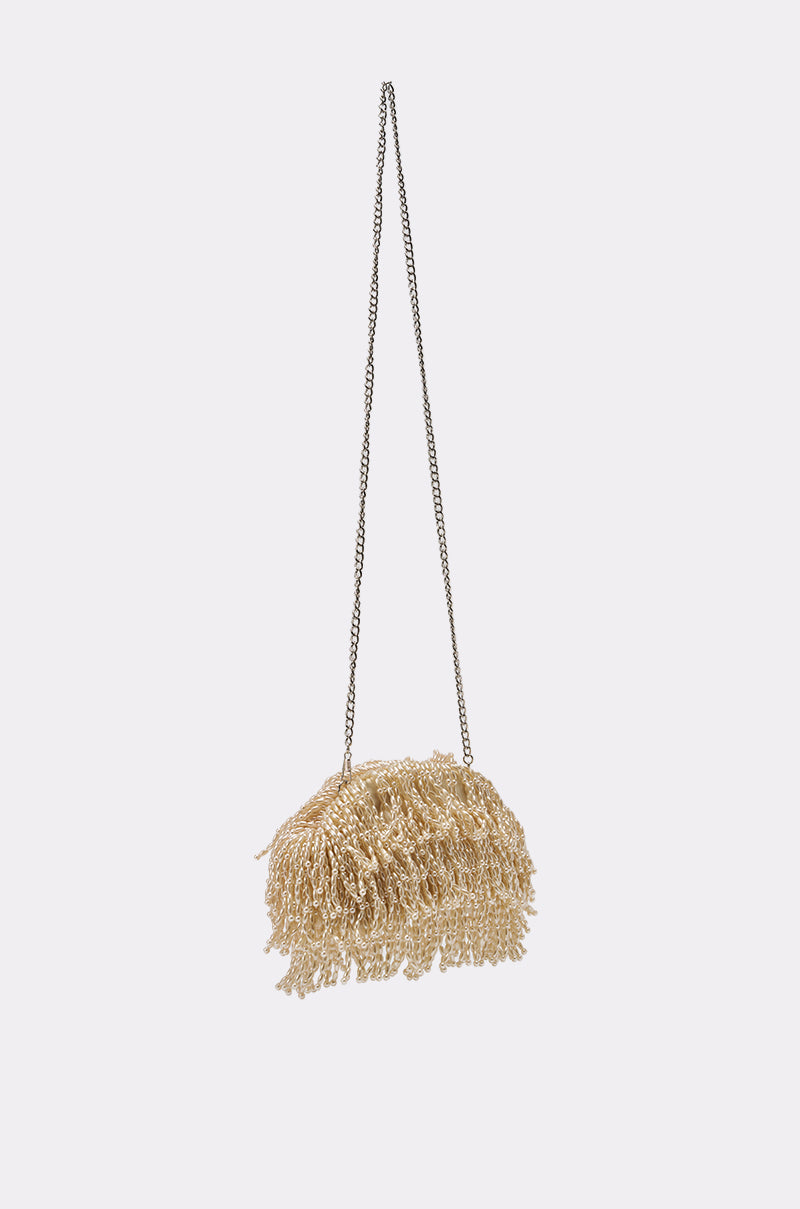 The ON AN ISLAND PEARL CLUTCH is a gold fringe handbag with a long chain strap, featuring shimmering golden tassels. Ideal as an evening or wedding accessory, it hangs elegantly against a plain light background. 4