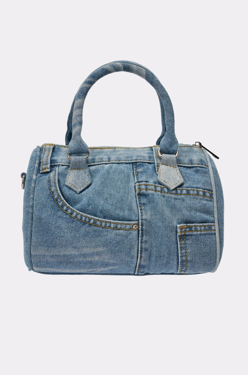 The NO BLUES DENIM PURSE is a mini bag made from blue denim, featuring jean-style pockets, seams, and handles for a playful look inspired by classic jeans. 3