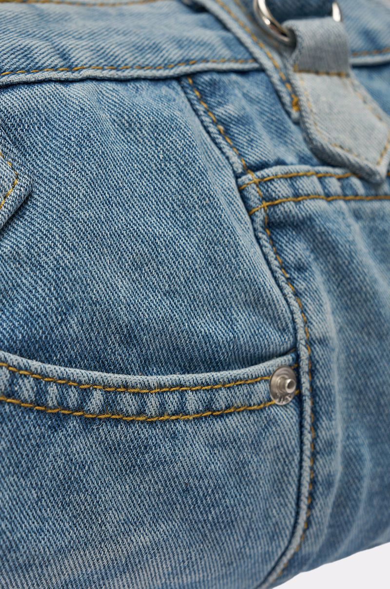 Close-up of the NO BLUES DENIM PURSE, a mini blue denim bag with a visible pocket, yellow stitching, and a metal button. 4