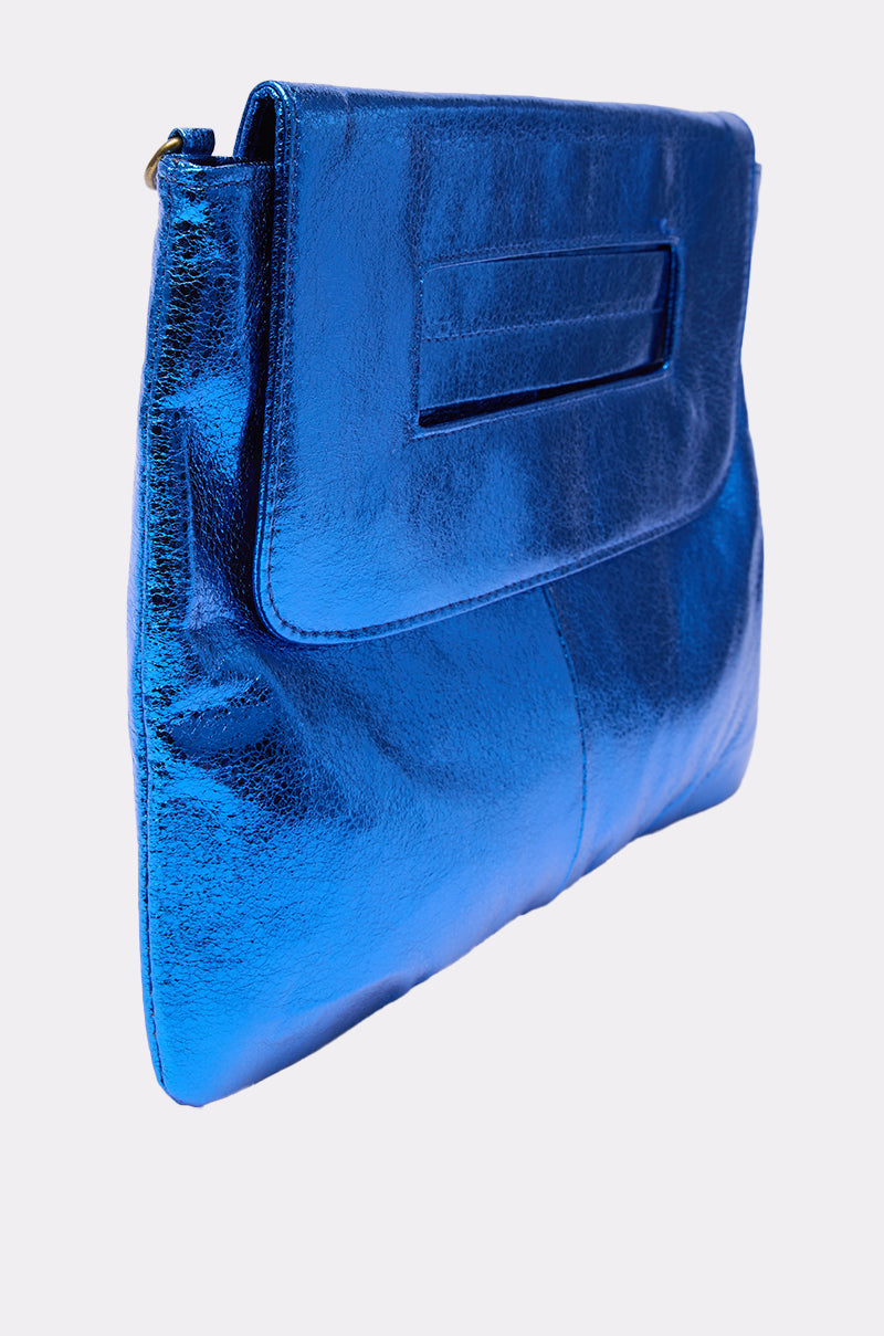The COSMIC COBALT OVERSIZED CLUTCH features metallic faux leather, a rectangular flap, and a slot handle, all presented against a plain light background. 2