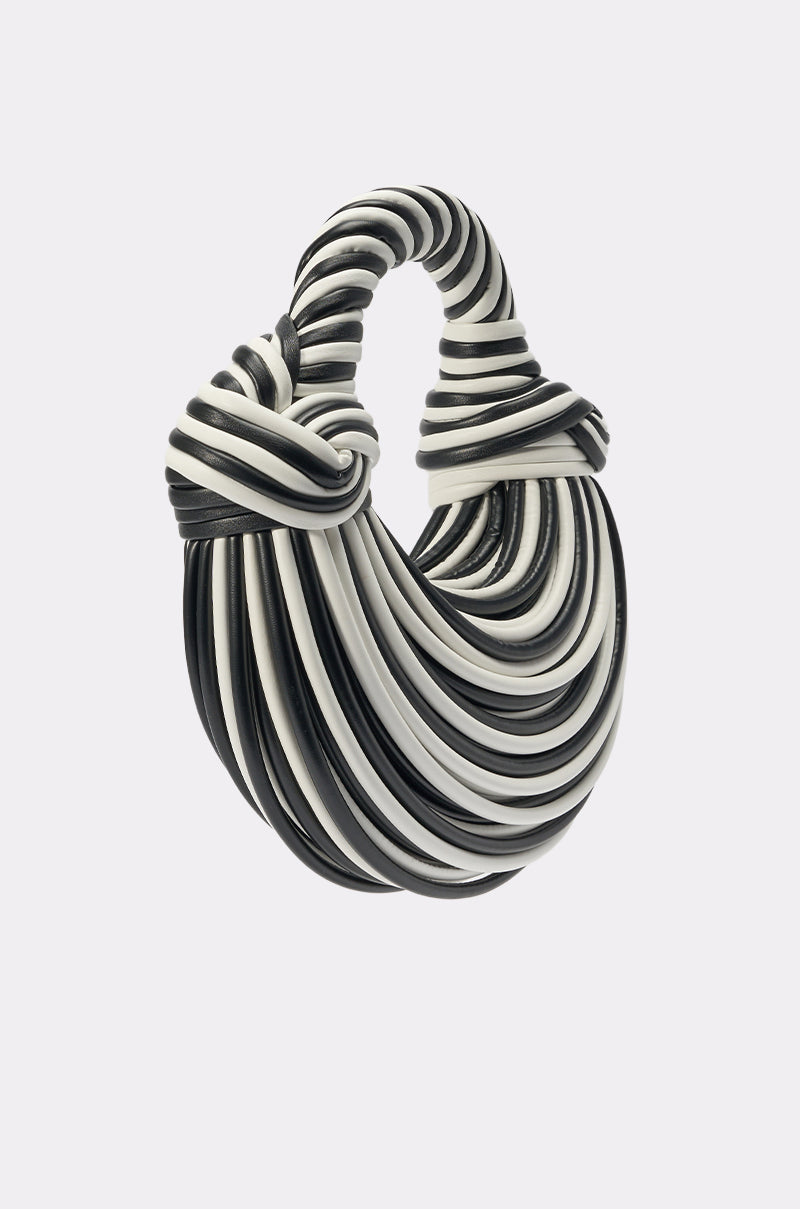 The COULDN'T DECIDE PURSE is a sculptural black-and-white striped bag, featuring thick cord-like loops layered into a curved open oval with a twisted top—resembling a bold statement fringe handbag. 2