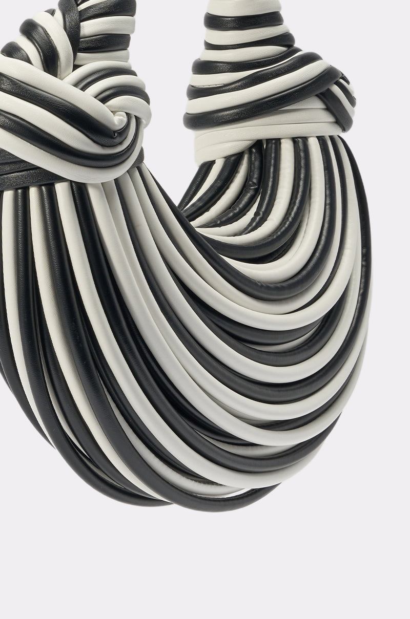 Close-up of a necklace with intertwined black and white tubular strands in a layered design—an eye-catching piece that pairs perfectly with the COULDN'T DECIDE PURSE. 3