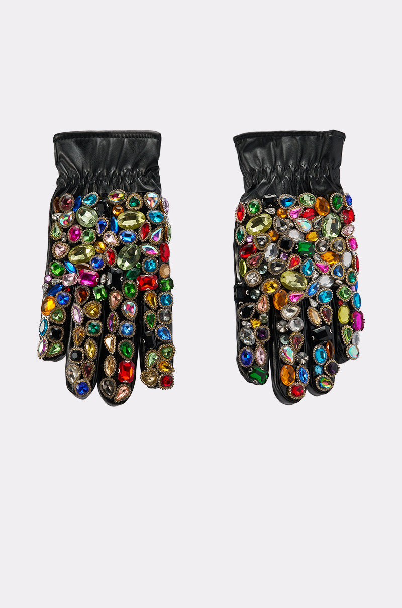 The LOVE YOU BLING GLOVES are black faux leather gloves decorated with colorful, oversized rhinestones and gems clustered densely on the tops and fingers, shown against a plain white background. 1