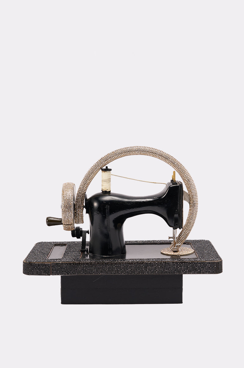 The SEW CUTE PURSE features a black vintage sewing machine design embellished with sparkling rhinestones on the wheel, base, and thread holder, all set against a plain white background. 3