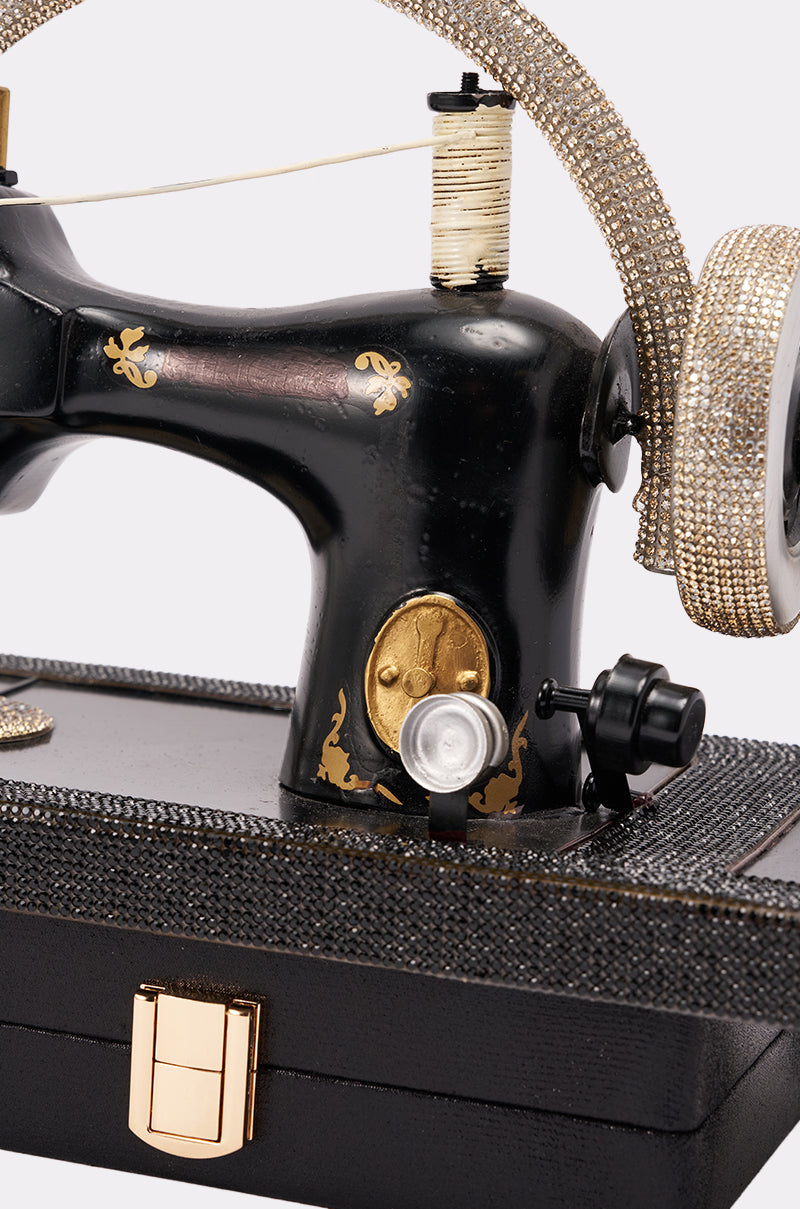 The SEW CUTE PURSE is a vintage-inspired black sewing machine purse with gold and rhinestone accents, a spool of thread, ornate details, a textured black base, and a gold latch. 4