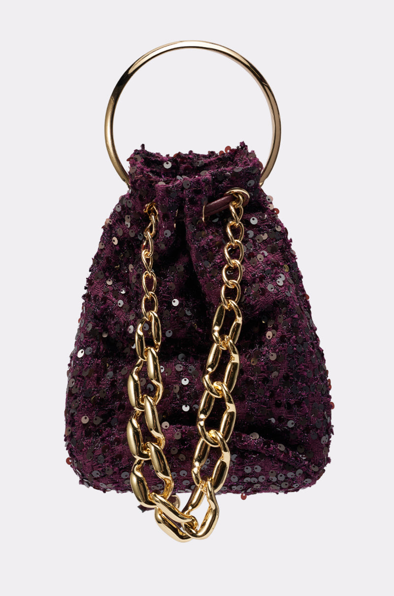 The KARY TWEED BUCKET BAG is a small, deep purple sequined mini bucket bag featuring a gold-tone top handle and chunky gold chain strap, shown against a plain white background. 1