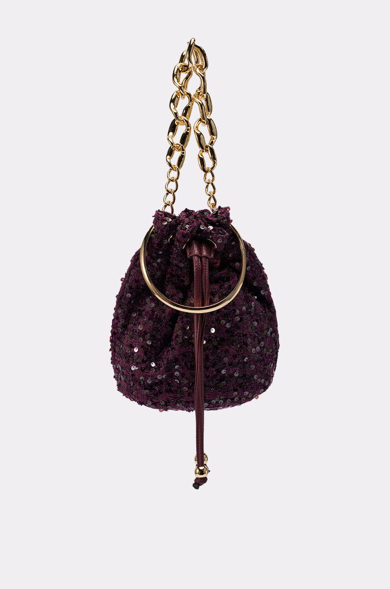 The KARY TWEED BUCKET BAG is a small purple sequin mini bucket bag featuring a gold metal ring and chunky gold-tone handle, shown against a plain white background.