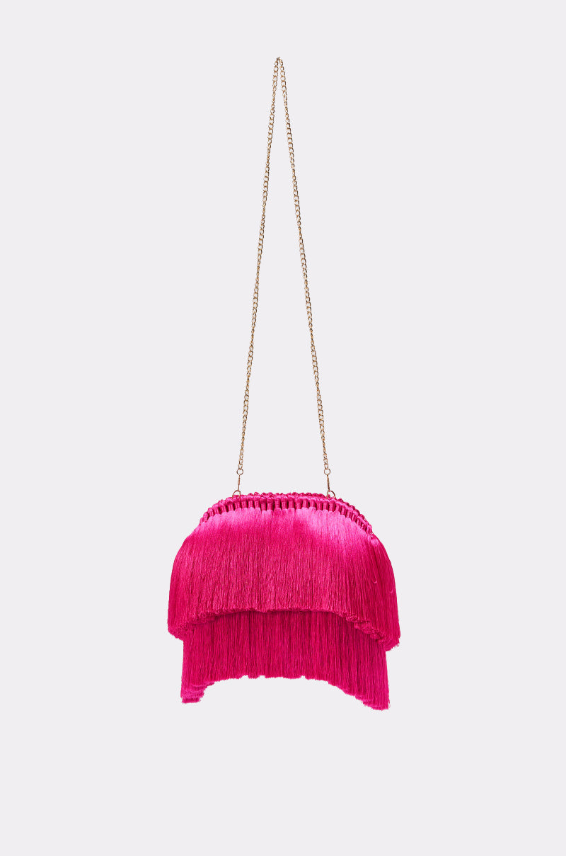 The RAZZLE DAZZLE TASSEL CLUTCH is a vibrant pink fringe party clutch featuring a gold chain strap, showcased on a plain light gray background. 2