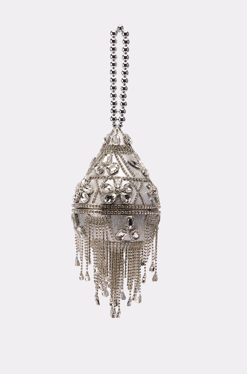 The DECO BLING BAG is a silver crystal evening bag with intricate designs, beaded handle, chain fringes, sparkling embellishments, and decorative patterns, shown against a plain light background.