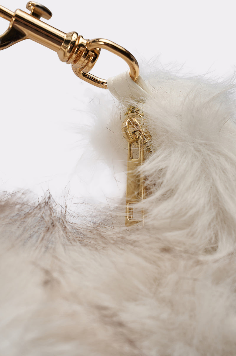 Close-up of the gold clasp and ring with a small gold charm on the WINTER SKY FAUX FUR PURSE, featuring soft, light-colored faux fur. 3