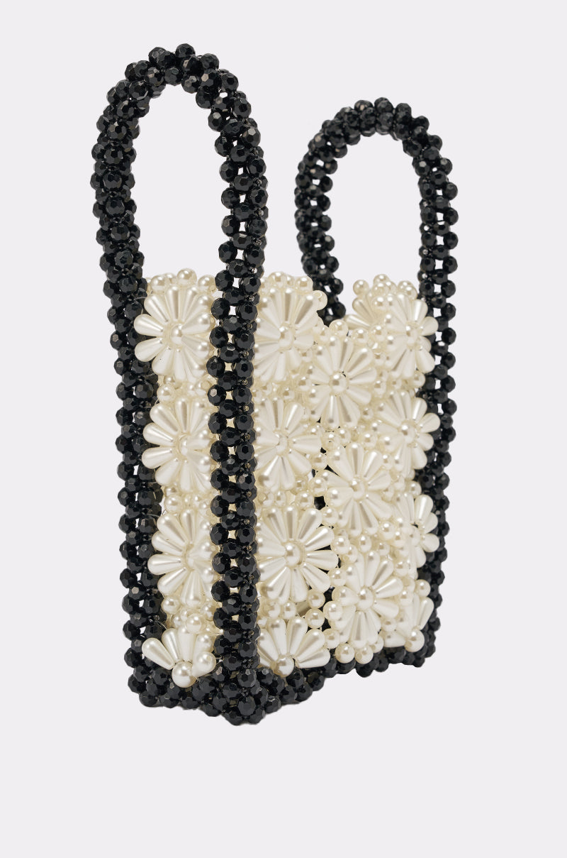 The ALL NIGHT LONG BEADED BAG is a small rectangular handbag with two handles, crafted from black and white beads in a floral pattern with black edges and white flower designs—an elegant choice for any evening bag collection. 3