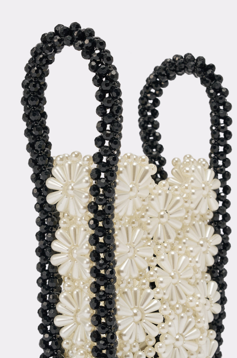 Close-up of the ALL NIGHT LONG BEADED BAG featuring white flower-shaped pearl beads on the main body and two black beaded handles, set against a plain light background. 4