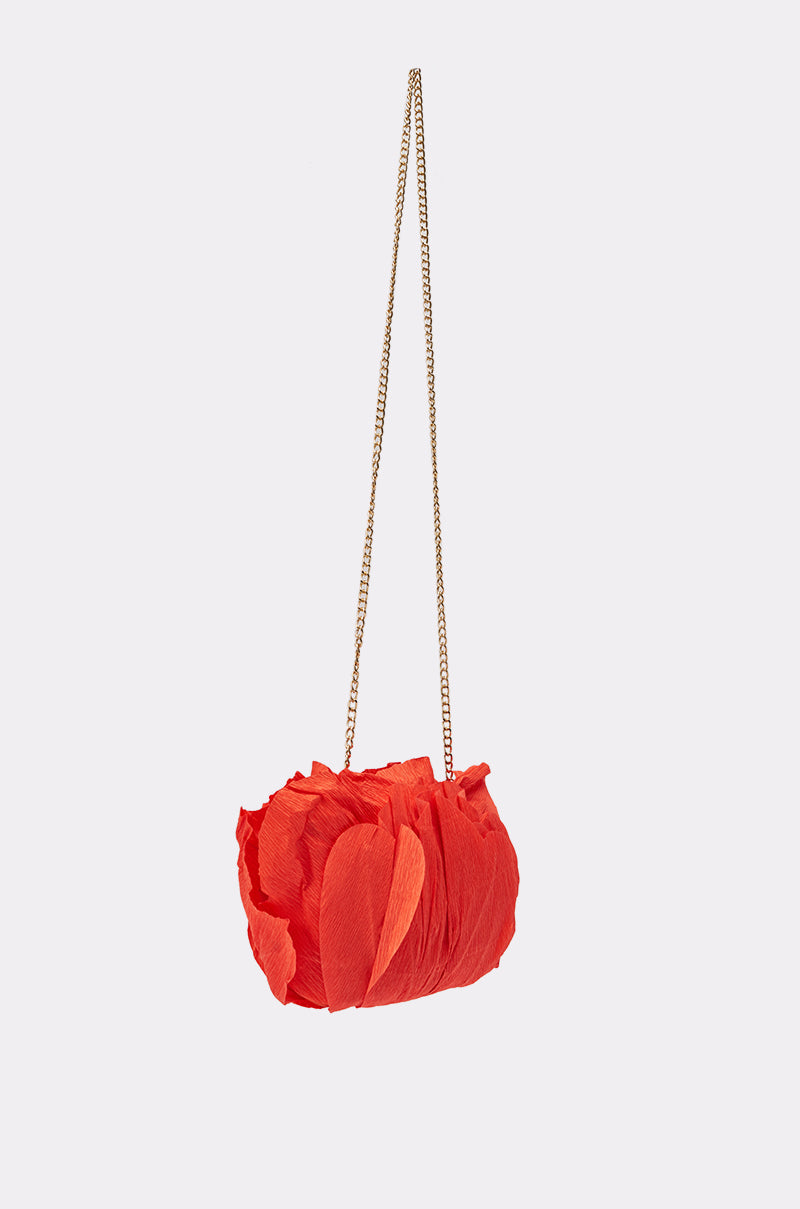 The FEEL MY VIBE CLUTCH is a small red floral bag featuring a textured petal-like design and a slim gold chain strap, shown against a plain light background. 4