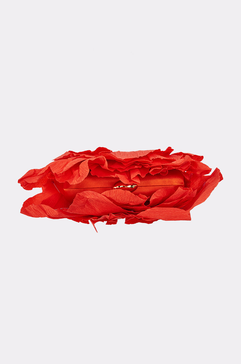 A red lipstick tube, partially wrapped in bright red tissue, rests on a light gray background—adding a bold accent when paired with the FEEL MY VIBE CLUTCH. 5