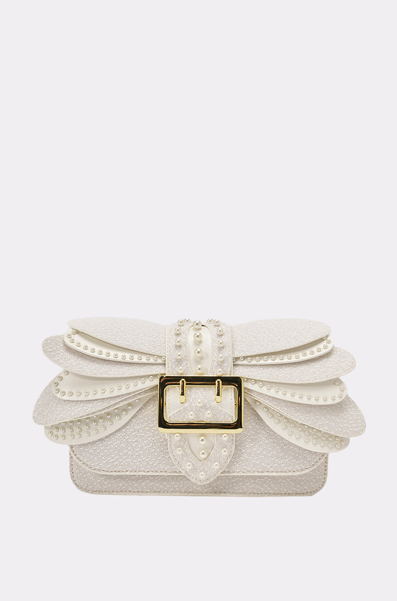 The LIKE A BUTTERFLY PURSE is a white evening bag with petal-inspired layers, pearl accents, a large gold buckle, and a textured glittery finish. Its structured shape and faux pearls make it a stunning statement accessory. 1