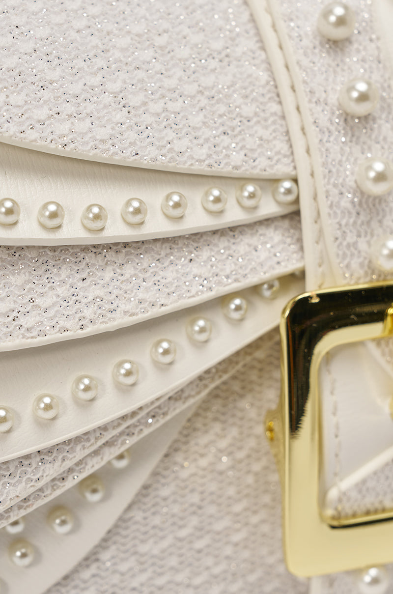 Close-up of the LIKE A BUTTERFLY PURSE featuring a white textured surface, rows of pearl-like studs, a shiny gold buckle, and a sparkly finish—perfect as a statement evening bag. 3