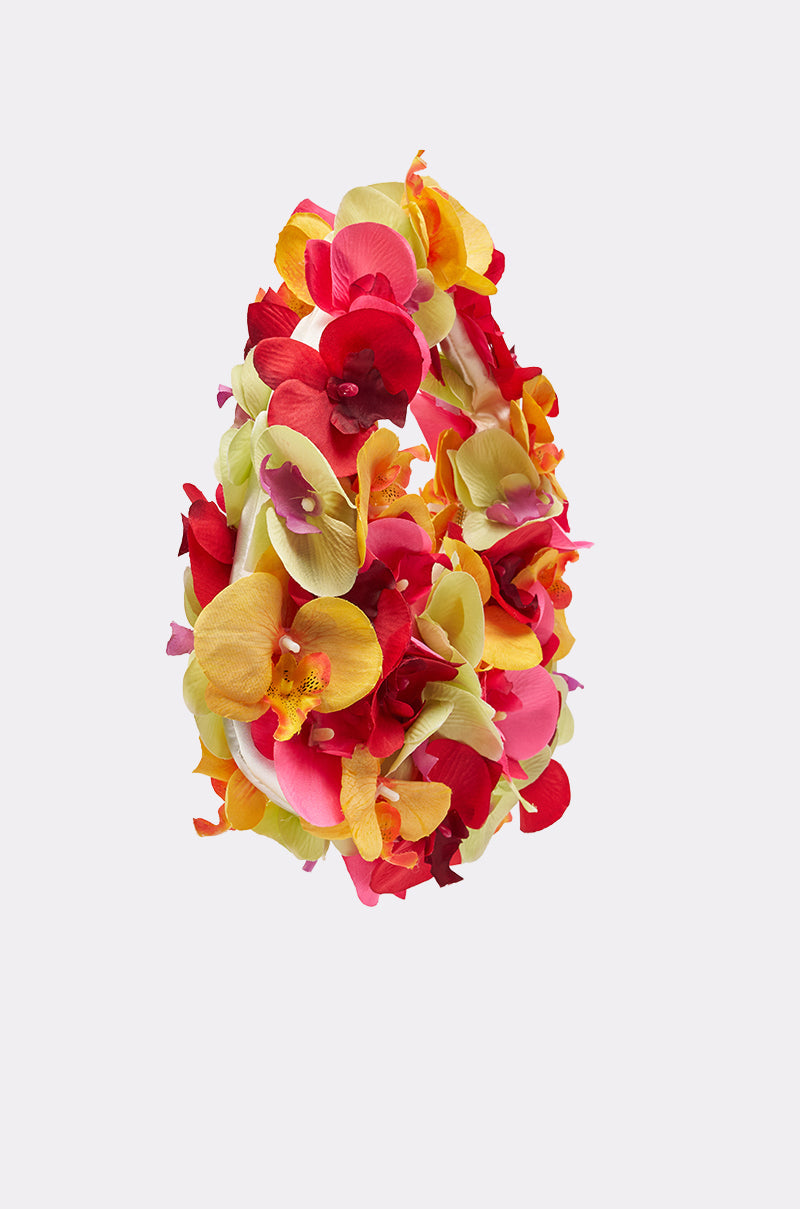 The ORCHID LOVE PURSE features a dense arrangement of artificial red, yellow, pink, and light green flowers covering its surface, set against a plain light background. 2