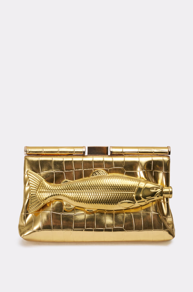 The GONE FISHIN CLUTCH is a gold croc-embossed bag with a detailed gold fish embellishment on the front and features a removable crossbody chain for versatile styling. 2